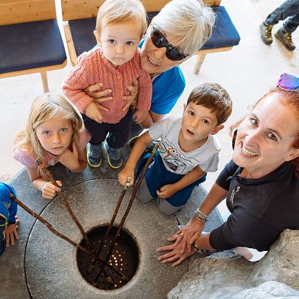 A group of people, including children and adults, gathered around a well with coins at the bottom.