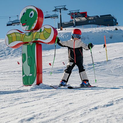 Kind auf Skiern an einem Kinderlift in Form einer Schlange.