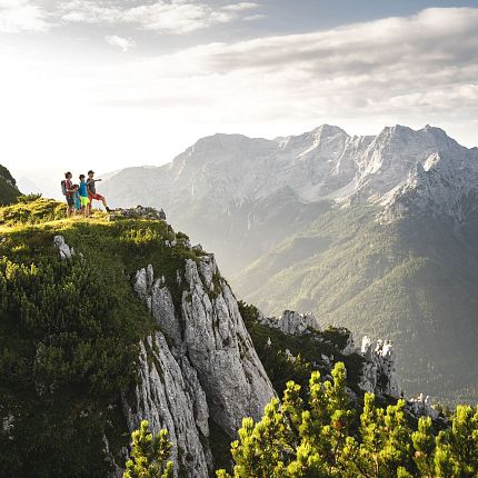 Hikers standing on a mountain ridge with mountains in the background.
