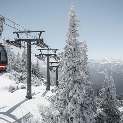 Rote Gondel einer Seilbahn in verschneiter Berglandschaft