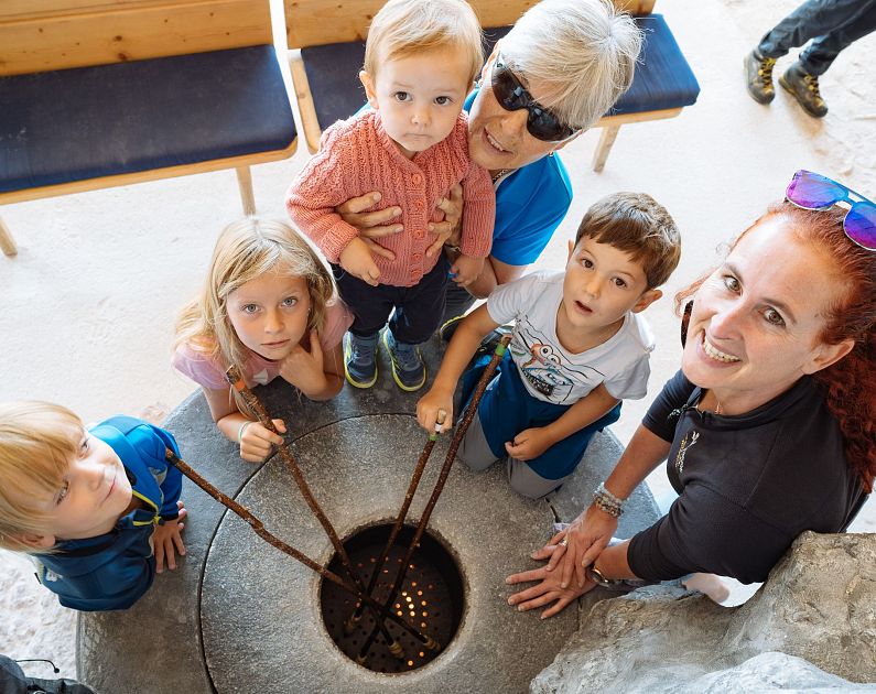 A group of people, including children and adults, gathered around a well with coins at the bottom.