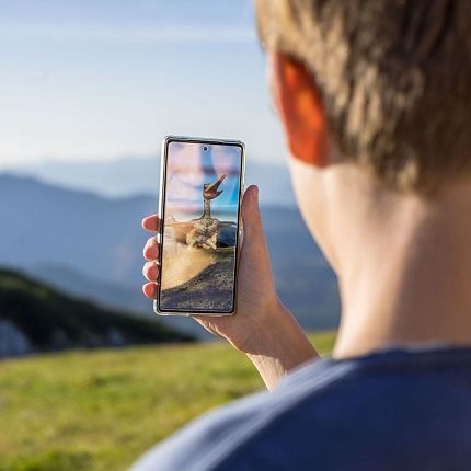 Person holding a smartphone displaying a mountain scene.