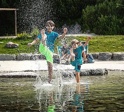 Three children splashing water in a park.