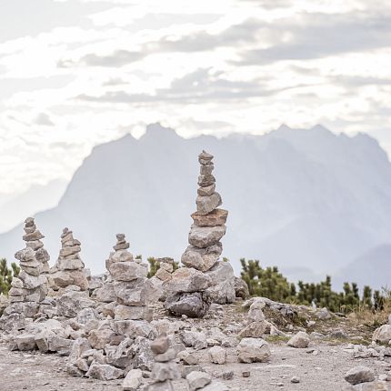 Steintürme vor einer Bergkulisse unter bewölktem Himmel, symbolisierend Ruhe und Balance in der Natur.