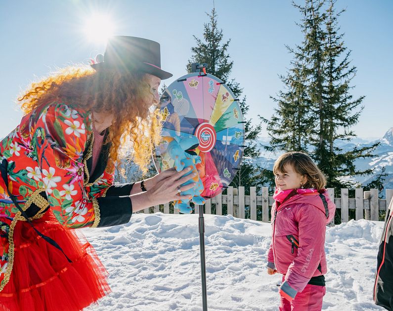 A person in colorful attire engaged in a game with two children in a snowy outdoor setting.