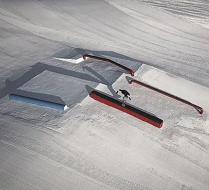 Snowboarder performing a trick on rails in a snowy terrain.